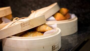 A wooden container with a lid, containing bread and a small item, possibly a pastry, on a dark surface.
