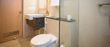 Un baño moderno con inodoro, lavamanos y cabina de ducha de vidrio.
