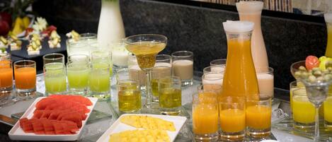 A buffet with various fruits, juices, and beverages.