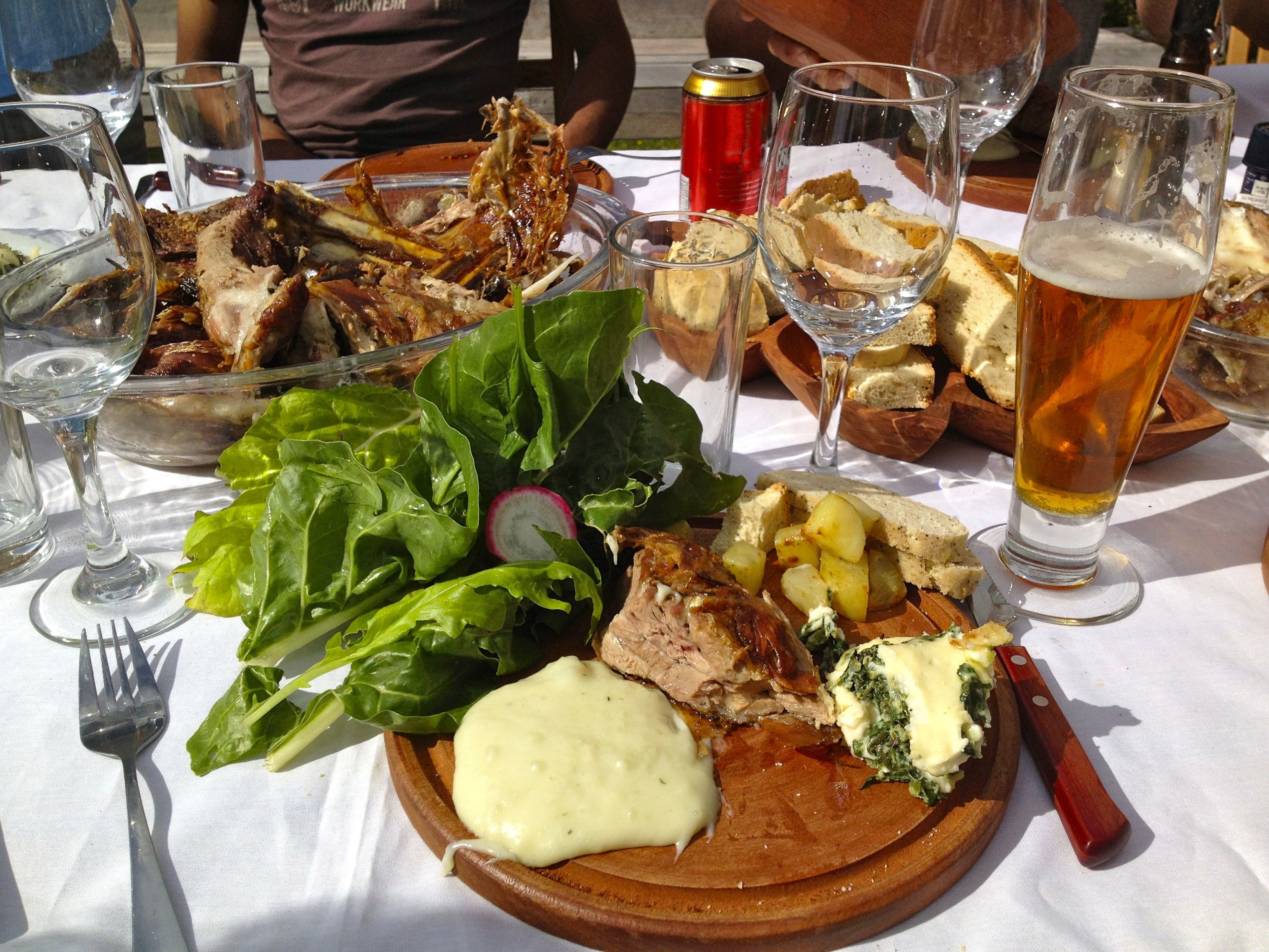 Uma refeição com diversos pratos, incluindo carne, batatas e vegetais, servida em uma tábua de madeira.