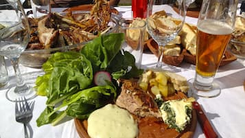 Uma refeição com diversos pratos, incluindo carne, batatas e vegetais, servida em uma tábua de madeira.