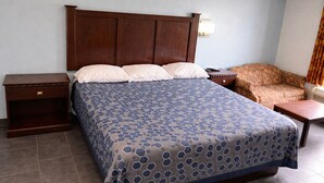Una habitación de hotel con una cama grande, una mesita de noche, una silla y una pequeña mesa.