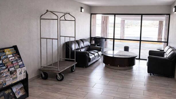 Una habitación moderna con un sofá modular, una mesita redonda, un carrito metálico y un atril para revistas.