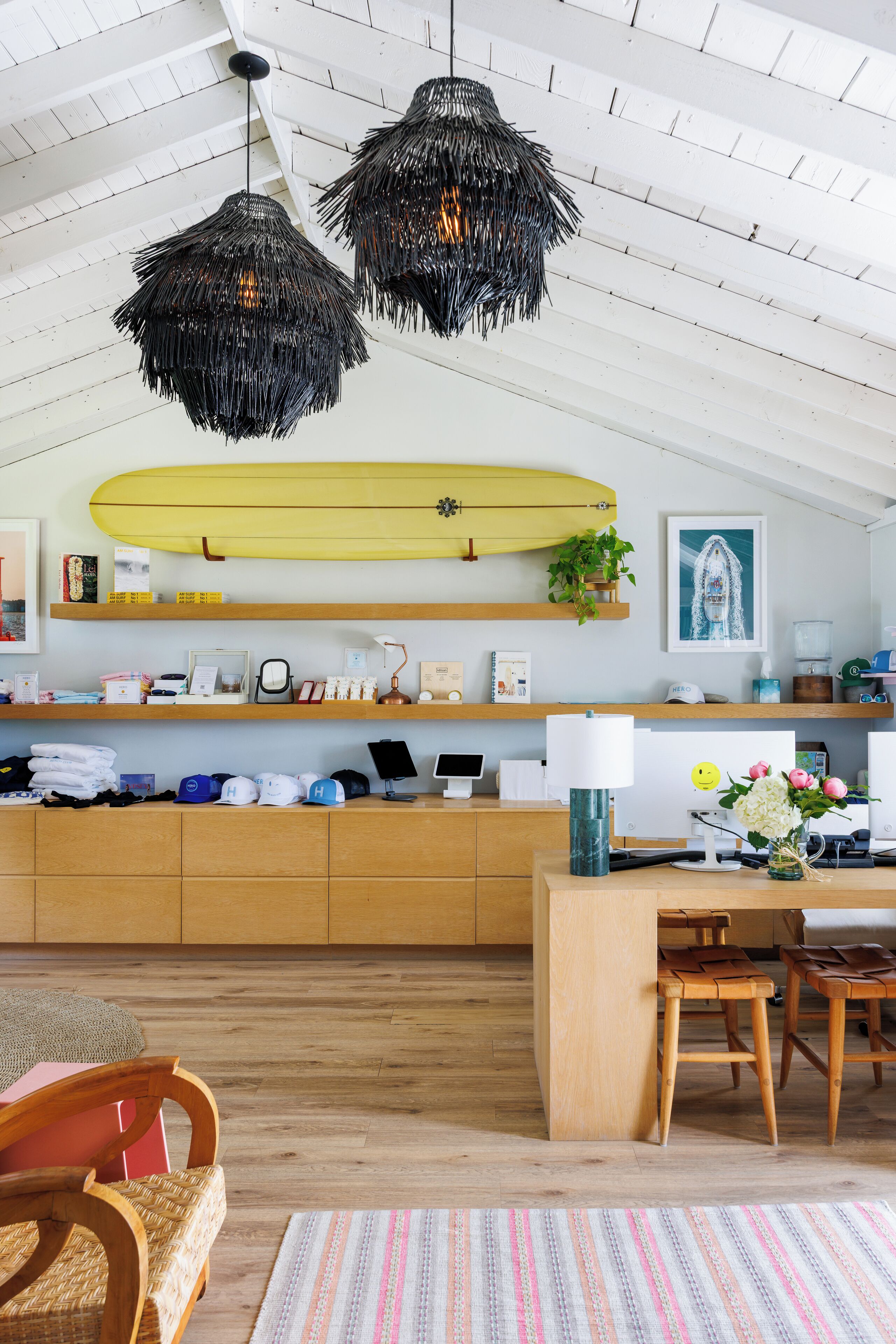 Une cuisine moderne avec des meubles en bois, une planche de surf et un coin repas agrémenté d’un tapis à rayures.