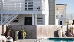 A two-story building with a pool, outdoor seating, and potted plants. - Hero Beach Club (Montauk)