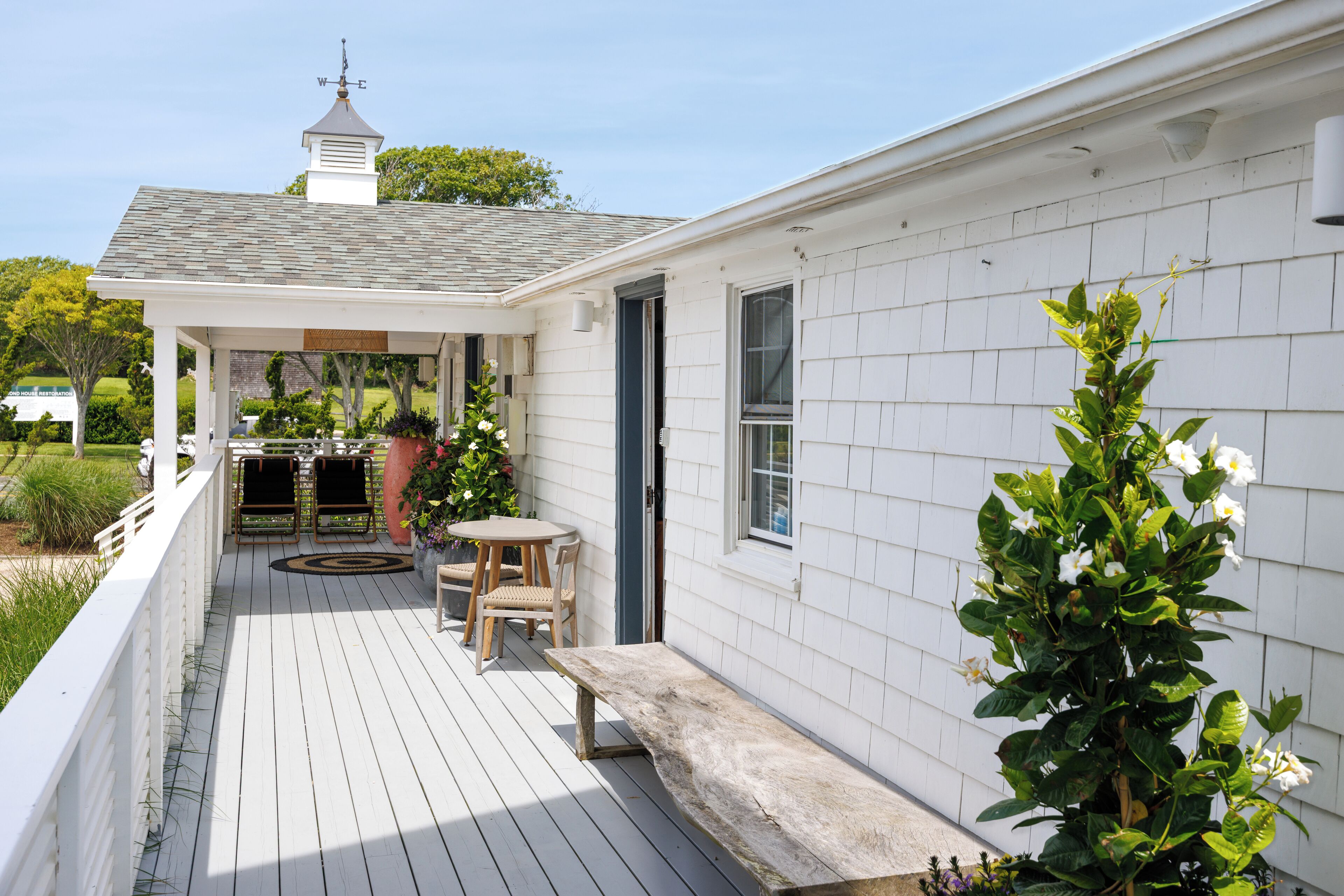 A covered porch with a bench, a table, and chairs.