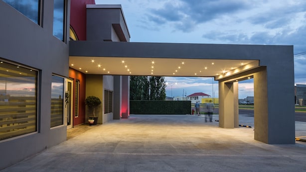 A modern building with a covered entrance, large windows, and a well-lit outdoor area.