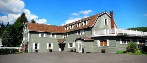 A two-story building with a large front porch, a chimney, and a balcony.