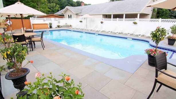 Una piscina con sillas de descanso y plantas en macetas.