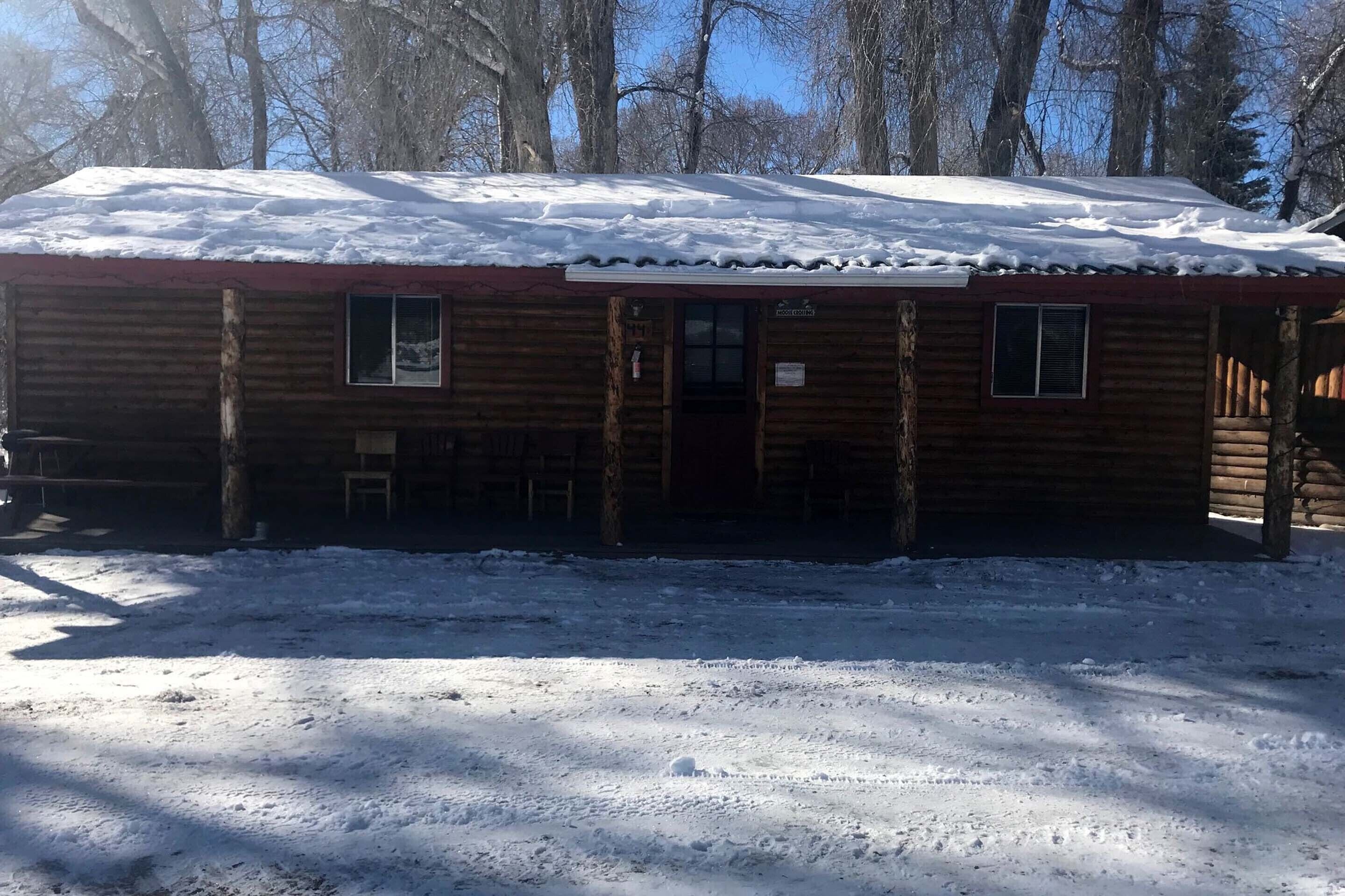 Een houten chalet met een sneeuwbedekte dak en een klein terras.