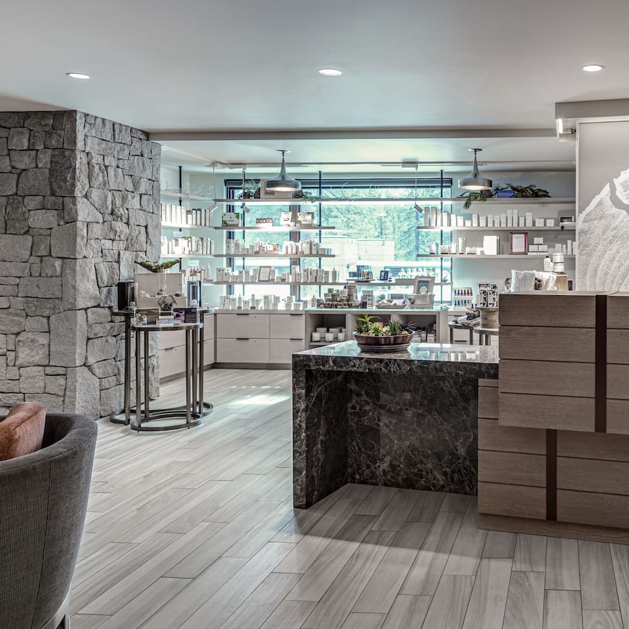 A modern reception area with a stone wall, a wooden reception desk, and a large window with a view of the outdoors.