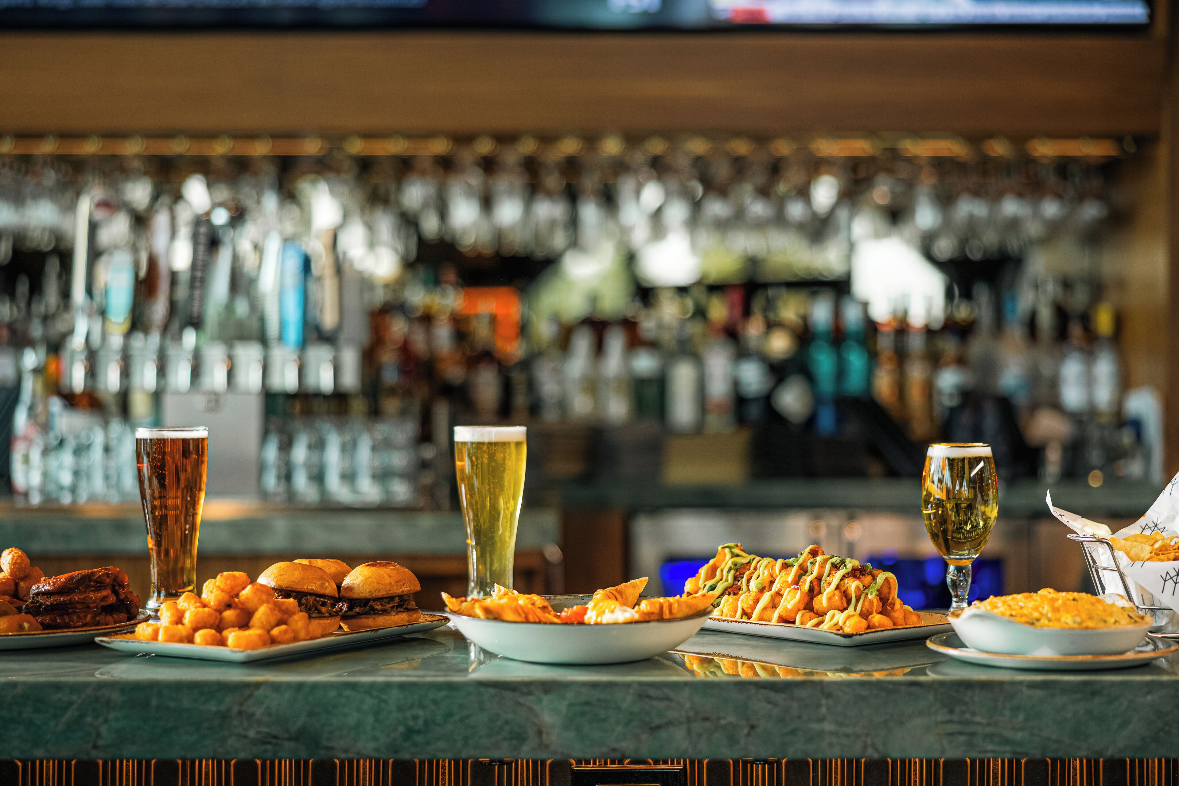 A bar counter with various food items and drinks.