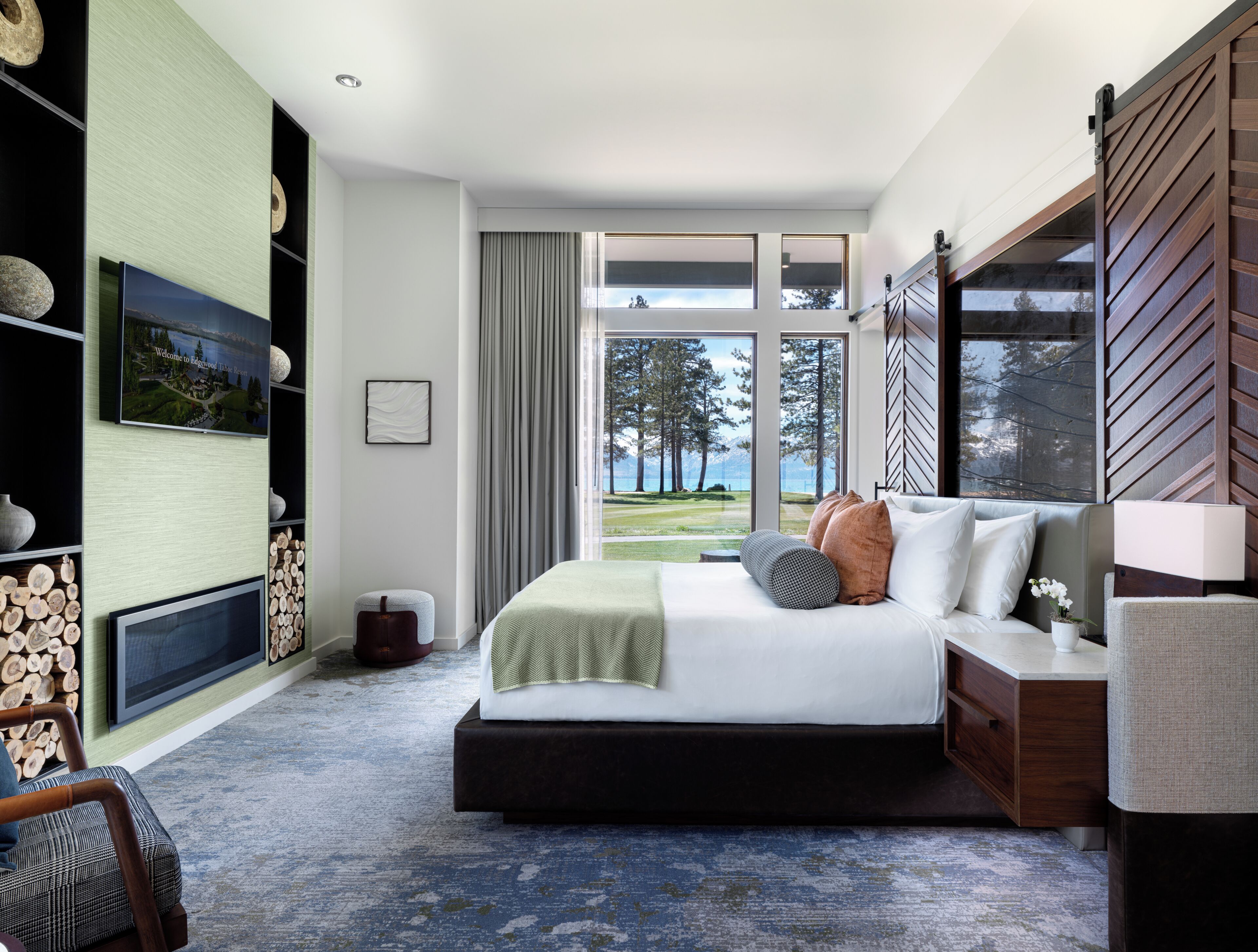 A modern bedroom with a large bed, a view of a golf course, and a wooden wall.