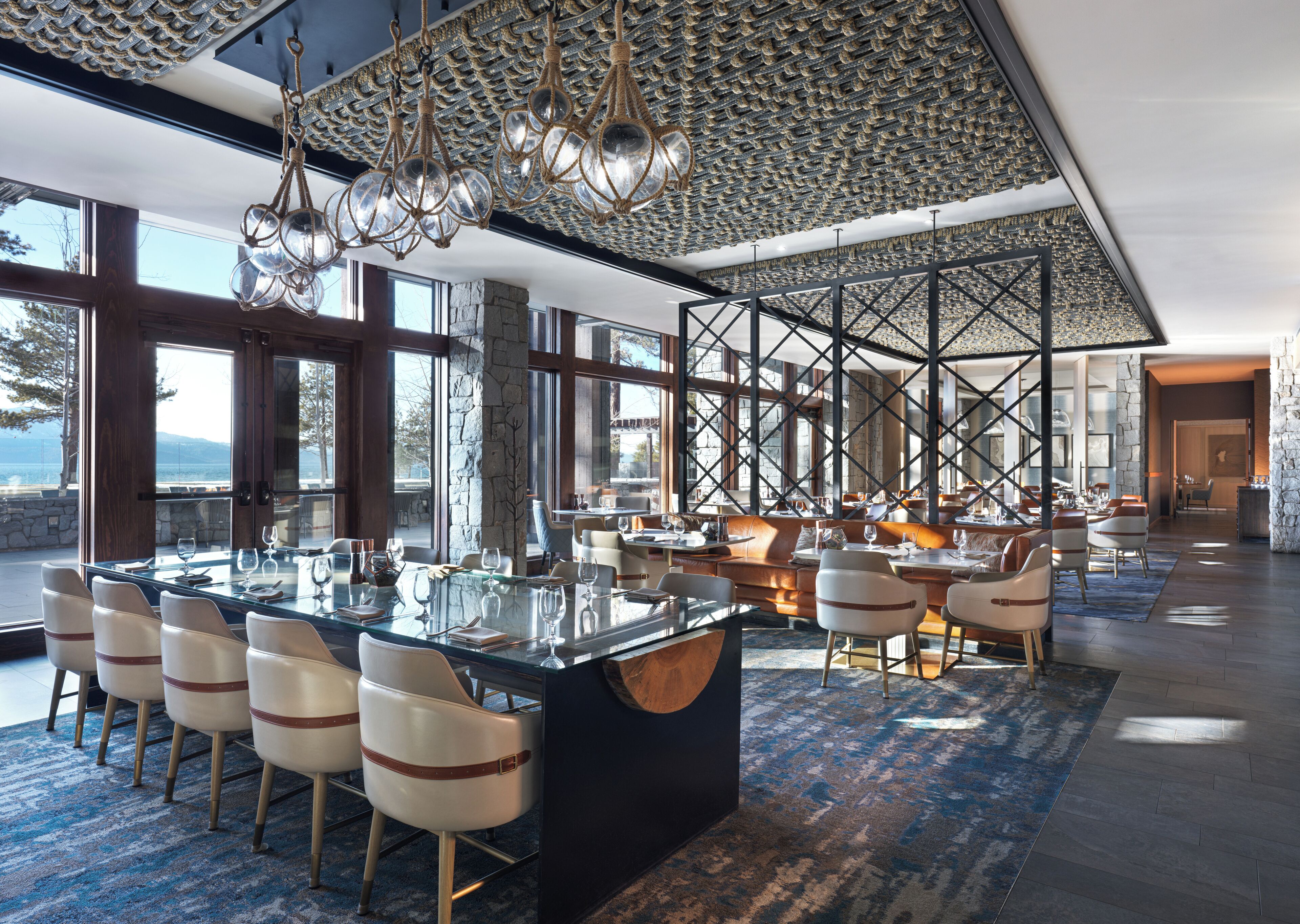 Un comedor espacioso con una isla grande, sillas modernas y vistas al exterior.