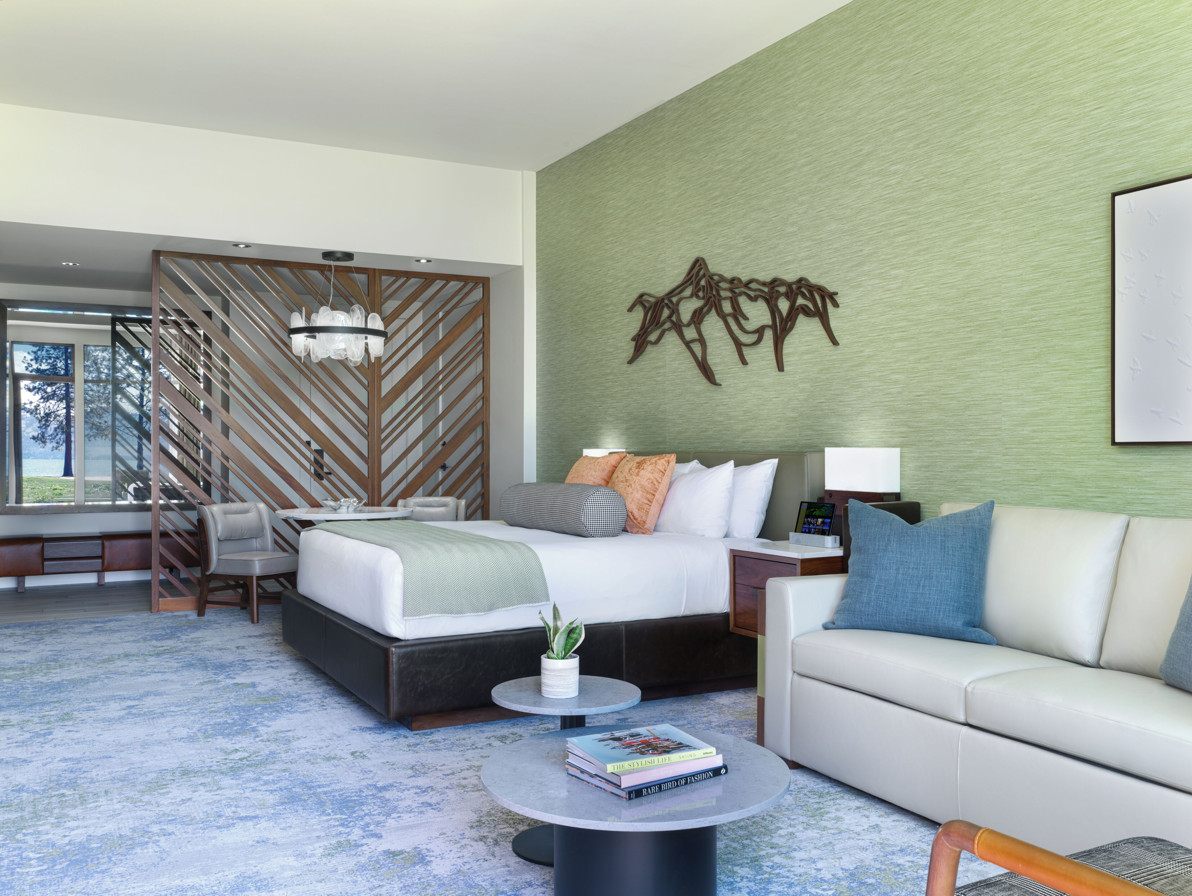 Une chambre d’hôtel moderne comprenant un lit, un canapé, une table basse et un élément décoratif mural.