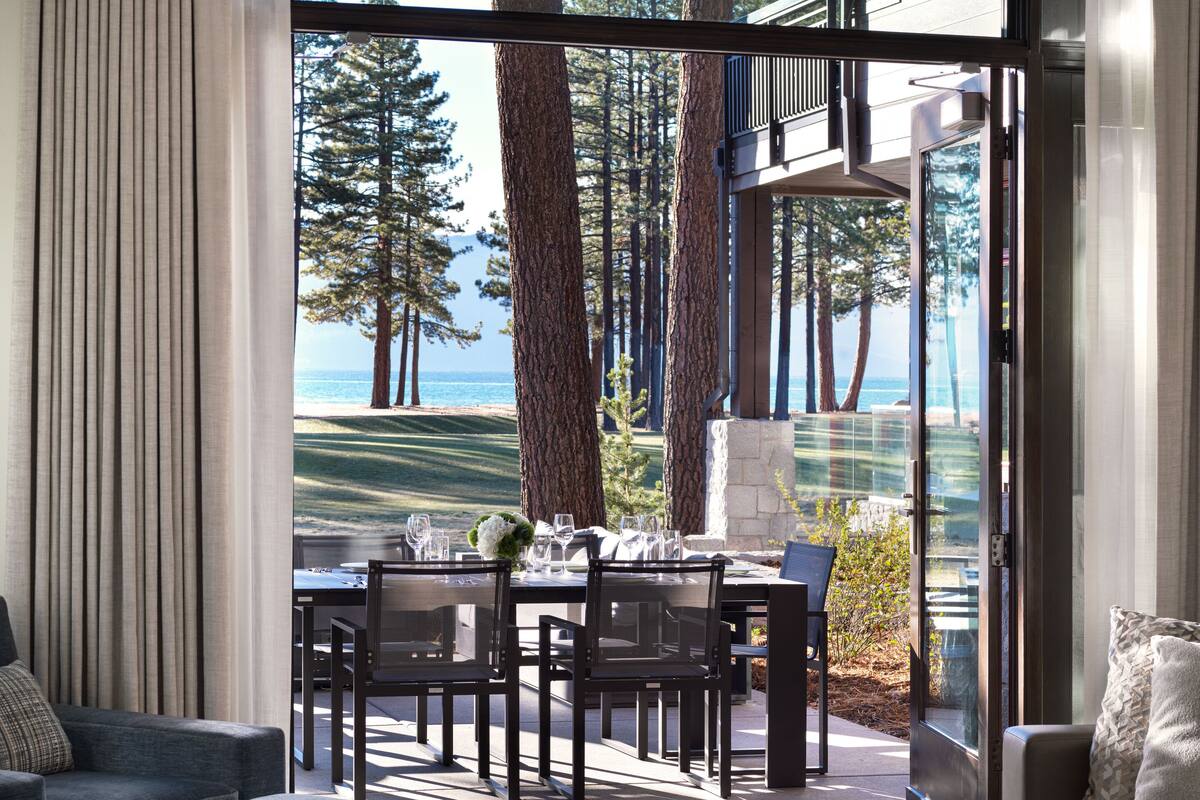 A modern living room with a dining area, large windows, and a view of the outdoors.