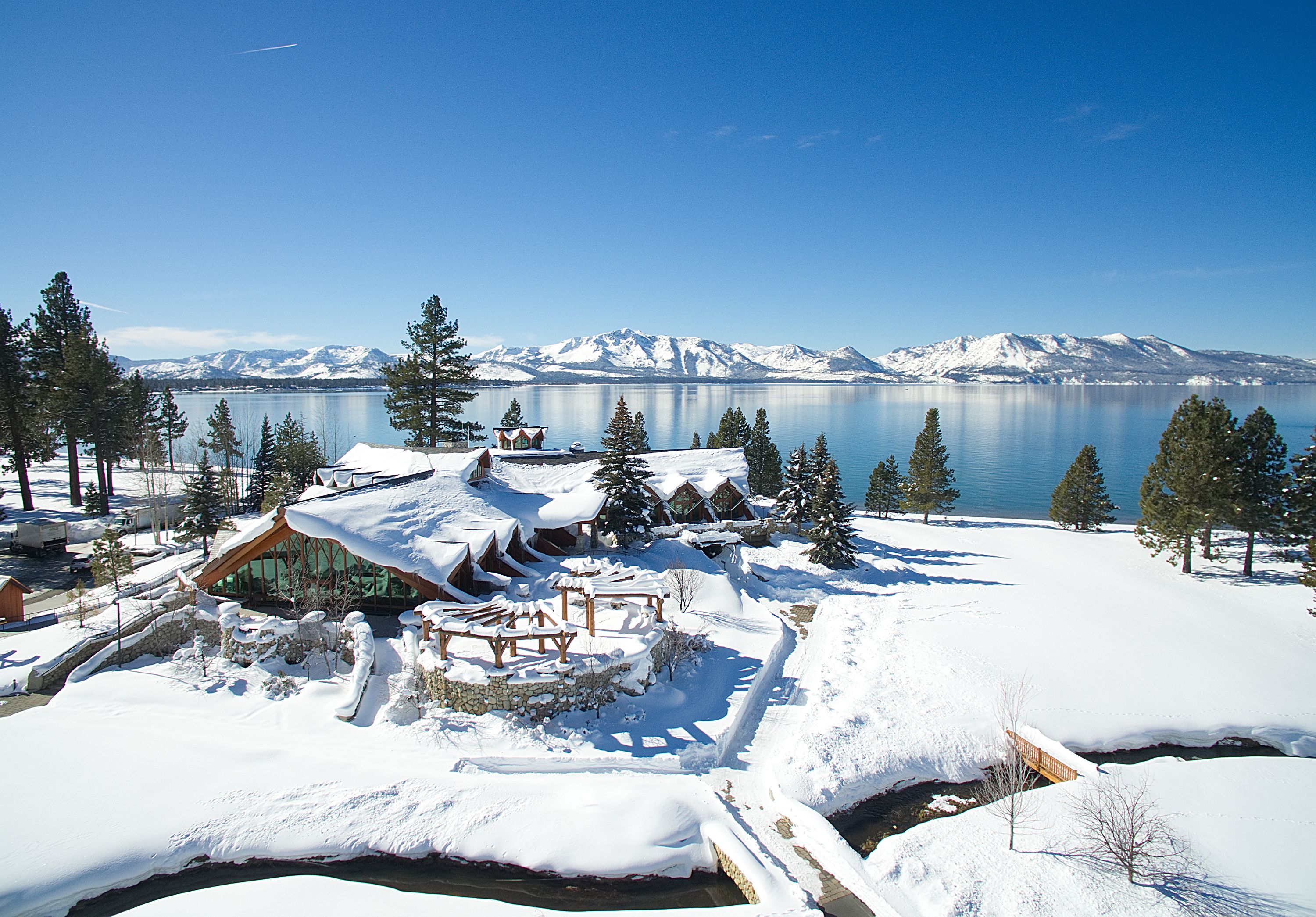 A snow-covered resort with wooden cabins and a lake view.