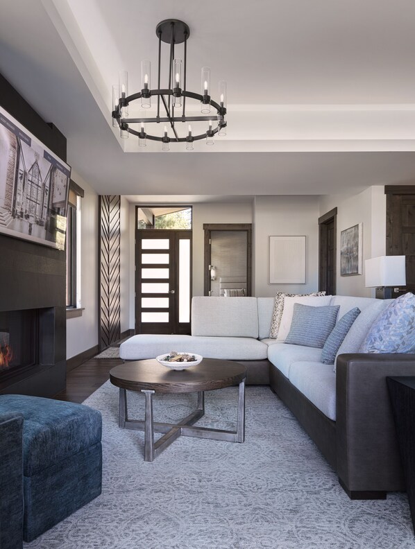 A modern living room with a sectional sofa, a coffee table, and a fireplace.
