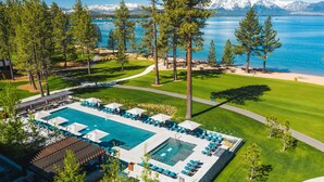 Vista aérea de un resort con una amplia piscina, un campo de golf y montañas al fondo.