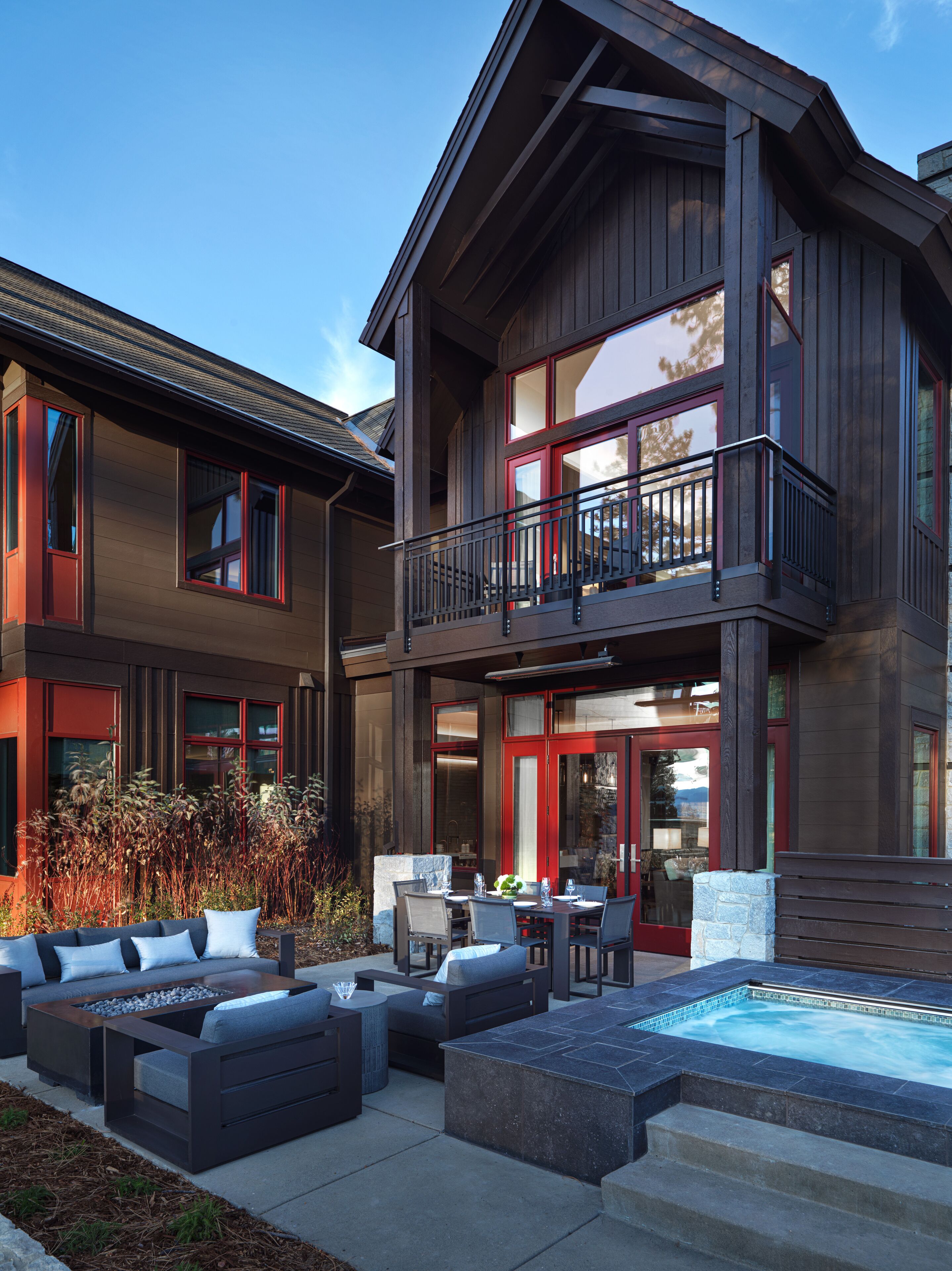 A two-story house with a balcony, outdoor seating, and a swimming pool.