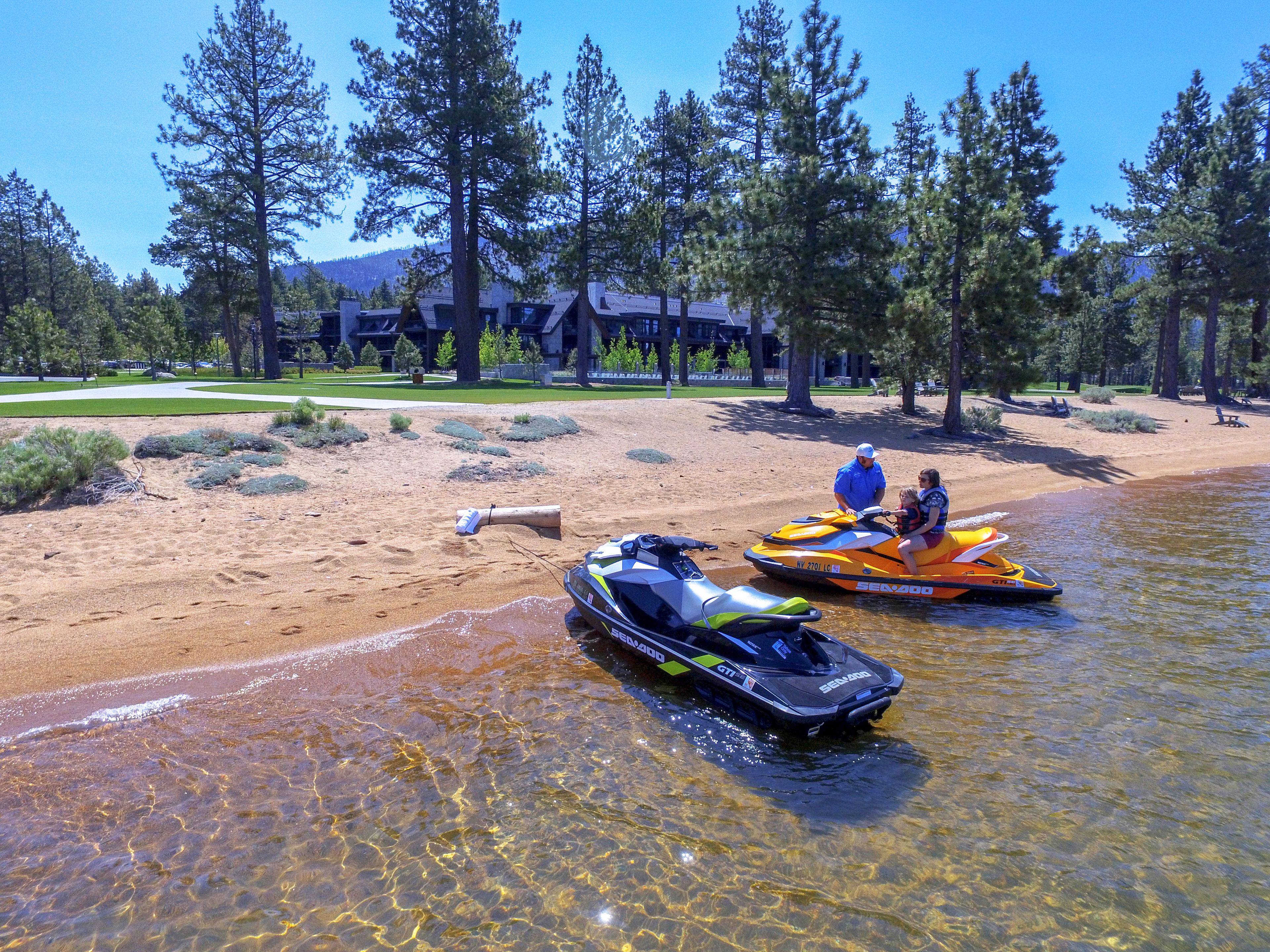 A sandy beach with two jet skis and a clear water body.