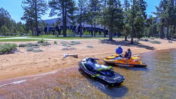 A sandy beach with two jet skis and a clear water body.