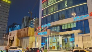 Een hotel met een moderne gevel, borden met de tekst "SWISS FLORA ROYAL HOTEL - RIYADH" en een zichtbare ingang met een hellingbaan voor toegankelijkheid.
