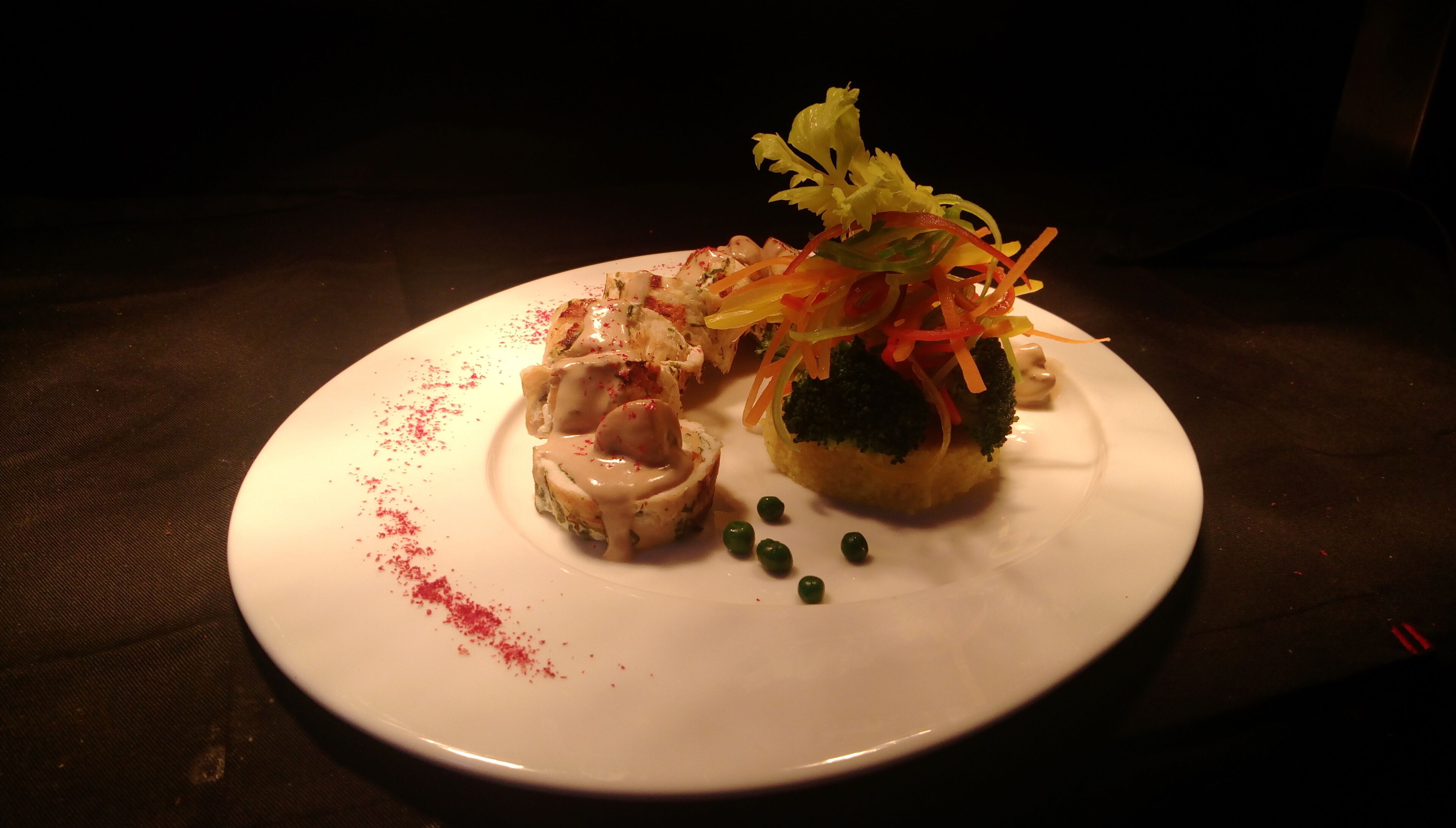 Un plato blanco con un guiso de mariscos, una guarnición de verduras y algunas guisantes.
