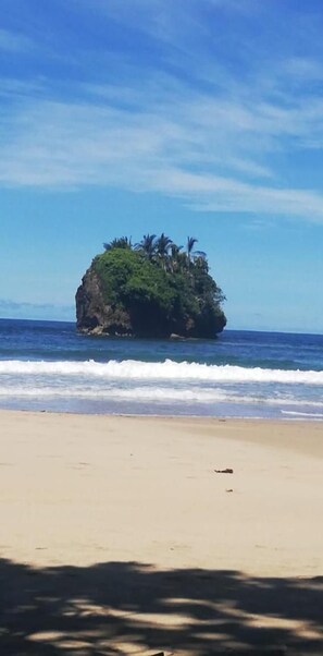 A beach with a small island in the distance, surrounded by calm ocean waves. - Hostal Cecilia (Cahuita)