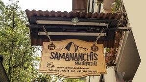 Ein Holzschild mit dem Namen 'Samananchis Machupicchu' und Kontaktinformationen.