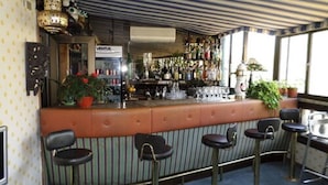 A bar area with striped seating, a counter with various bottles, and a sign that reads "VENTUS". - Foresta Hotel (Santiago)