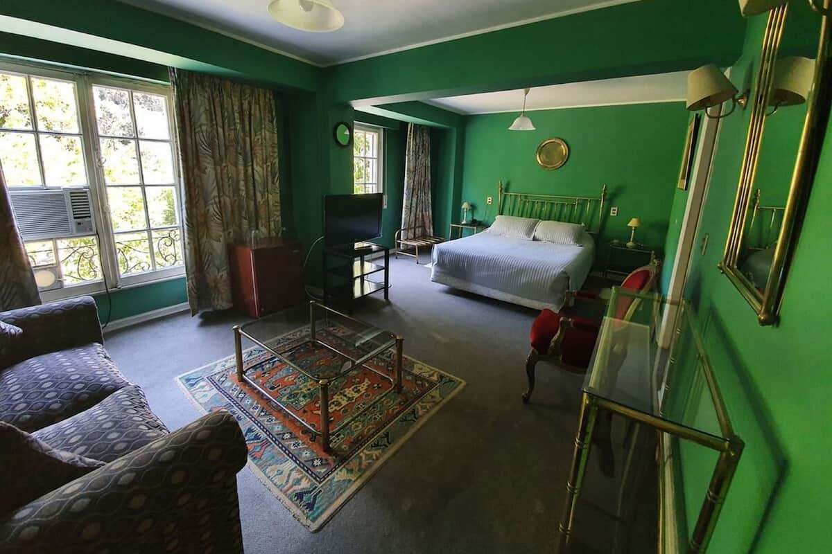 A room with a bed, a TV, a desk, and a chair.