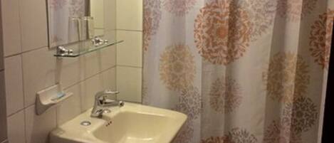 A bathroom with a sink, mirror, and shower curtain.