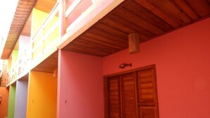 Un edificio con fachada rosa, una puerta de madera y un balcón con barandilla de madera.