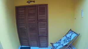 Una puerta de madera con una placa numérica con forma de pez, una lámpara colgante y un sillón estampado.