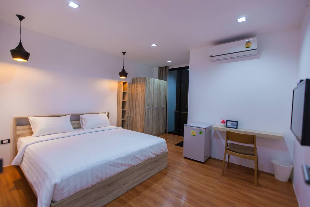 A modern hotel room with a wooden bed, a desk, and a chair.