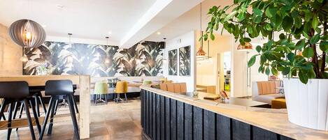 Una cocina moderna con una isla central, taburetes de bar y una planta grande en maceta.