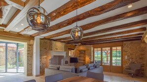 Un vaste espace de vie agrémenté d’une cheminée en pierre, d’une grande table à manger en bois et d’un coin salon confortable.