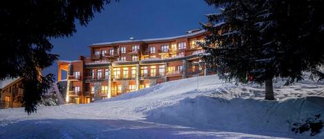Un hôtel à plusieurs étages avec une piste de ski au premier plan.
