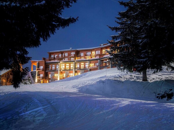 A multi-story hotel with a ski slope in the foreground.