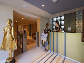 A reception area with a golden statue, a reception desk, and a patterned wall.