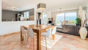 Eine moderne Küche mit Essbereich, großen Fenstern und Blick ins Freie.