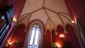 Une pièce dotée d’un plafond voûté élevé, de fenêtres en arc de cercle et d’appliques murales.