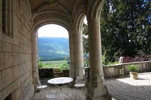 An outdoor patio with a stone archway, a round table, and two chairs. - Apartment in Serrieres en Chautagne with Pool (Serrieres en Chautagne)