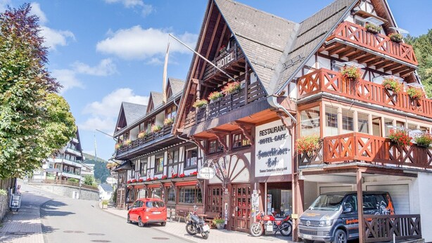 Un bâtiment traditionnel en bois, avec une enseigne indiquant qu’il s’agit d’un restaurant et d’un café-hôtel.