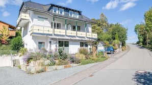 Un bâtiment à deux étages avec une enseigne indiquant « FERIENHAUS BECKER » et une voiture garée devant.