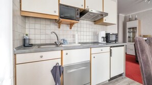 Une cuisine moderne avec des meubles blancs, un lave-vaisselle Bosch, un four à micro-ondes et une machine à café.