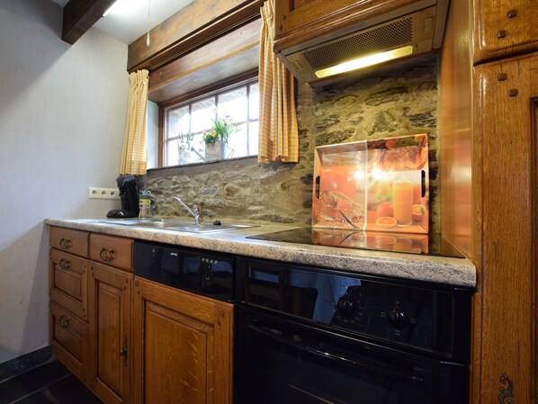 A kitchen with wooden cabinets, a granite countertop, a stainless steel sink, and a built-in oven. - Gite at the Calm way in the Center (Bastogne-Rachamps)