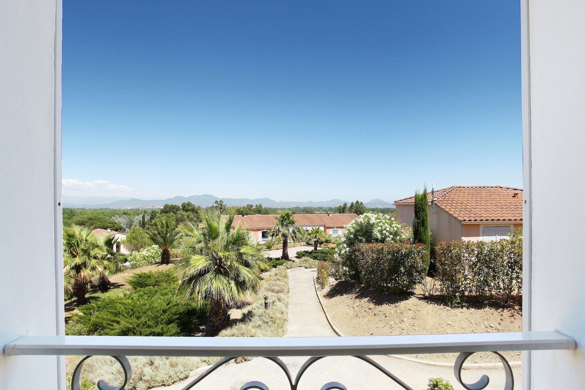 A balcony with a view of a residential area, including houses and greenery.