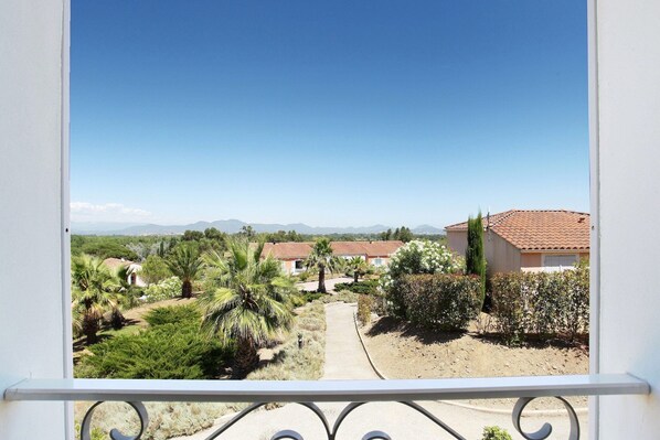 A balcony with a view of a residential area, including houses and greenery.